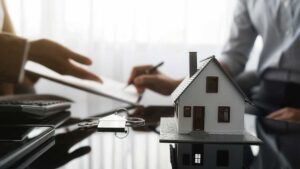 Homeowner reviews insurance documents beside household photos, receipts, and a calculator at a kitchen table