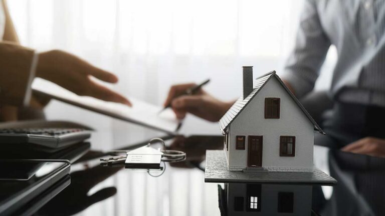 Homeowner reviews insurance documents beside household photos, receipts, and a calculator at a kitchen table
